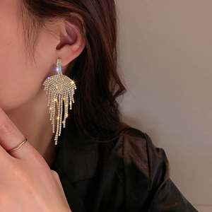 Close-up of sparkling leaf-shaped fringe earrings with long rhinestone tassels on model