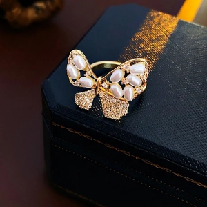 Bague nœud dorée avec perles et cristaux sur un écrin à bijoux noir de luxe