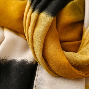 Detailed close-up of yellow and black tie-dye gradient fabric texture with fine stitching