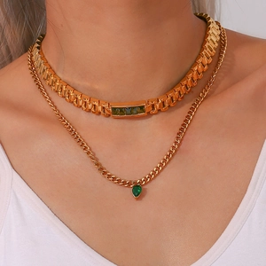 Layered gold chain necklace with emerald green gemstone pendants on a fashion model