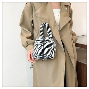 Detail of zebra print plush crossbody bag with golden chain strap on a khaki coat