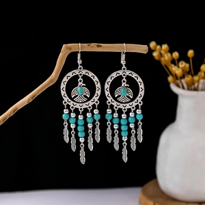 Detailed close-up of bohemian silver earrings with turquoise beads and eagle charms
