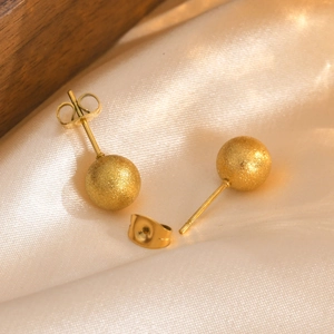 Detailed close-up of gold frosted round bead earrings on elegant champagne silk fabric