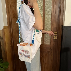 Détail du mini sac en toile avec broderies graffiti et bandoulière en corde tressée
