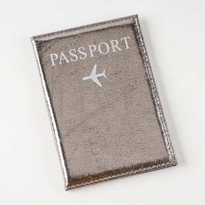 Macro shot of silver cracked leather passport holder with embossed passport text and airplane