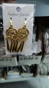 Detail view of bohemian gold rose earrings with long metal tassels on card packaging
