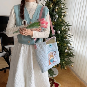 Detail of blue quilted tote bag with cute embroidery and pink adjustable strap