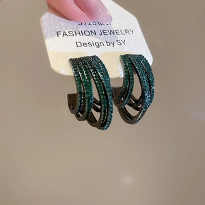 Macro detail of emerald green zircon multi-layer C-shape hoop earrings with dark metal finish