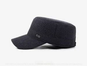 Detail of dark grey winter flat cap featuring twill fabric and side metal brand plate