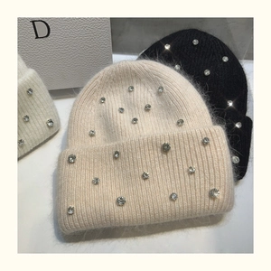 Detail of three knit beanies in cream, white, and black with sparkling rhinestone accents
