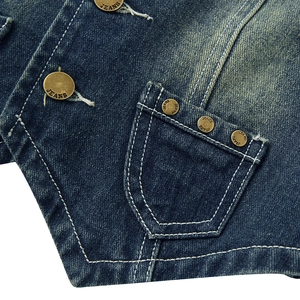 Dettaglio macro del gilet in denim blu scuro con cuciture a contrasto e bottoni vintage