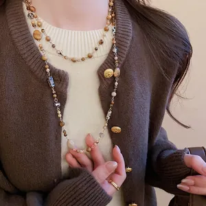 Layered beaded necklace in earth tones on brown knitwear featuring gold-plated hardware
