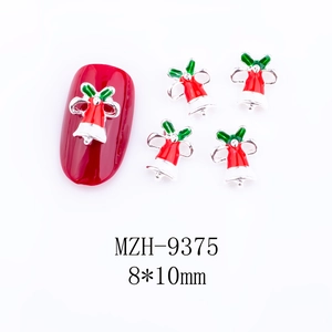 Details von Weihnachtsglocken-Nagelkunst-Anhängern mit grünen Schleifen auf Maniküre