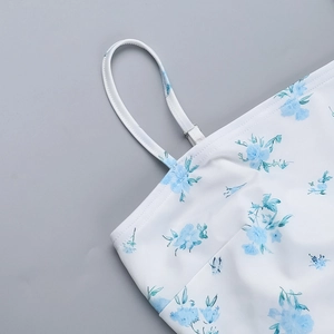 Detail of white dress with blue floral print featuring thin spaghetti straps and clean stitching