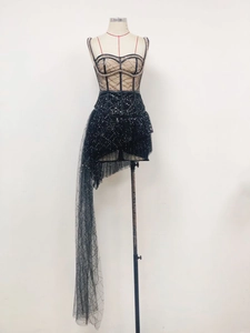 Detail of black sequined corset dress featuring asymmetrical mesh train on mannequin