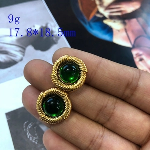 Détail macro de boucles d'oreilles rétro dorées avec émail vert et texture torsadée