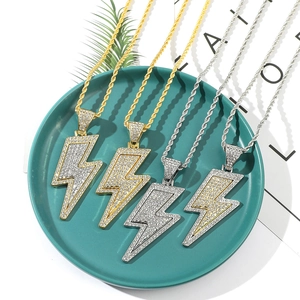 Flat lay of gold and silver hip hop lightning pendants with crystals on a green tray