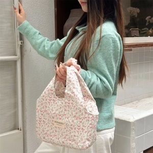 Detail showing hand holding a floral canvas lunch bag with pink flower pattern