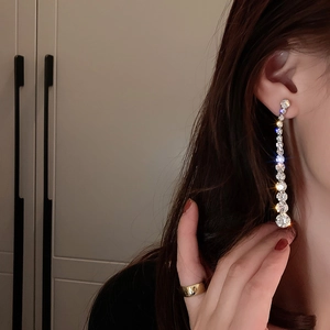 Close-up of elegant long silver tassel earrings with sparkling rhinestones on model