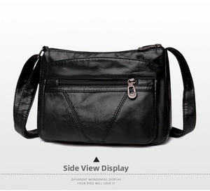 Détail d'un sac bandoulière en cuir souple noir avec plusieurs fermetures éclair