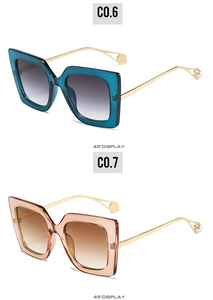 Detail view of large square sunglasses with gold metal temples and pearl tip accents