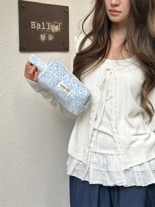 Detail of blue and white leopard print plush makeup bag held by a model