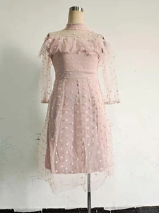 Detail of pink polka dot mesh dress featuring elegant ruffle neck and waist cinching