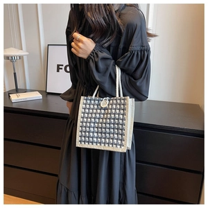 Close-up of a checkered linen tote bag with rope handles and button closure detail