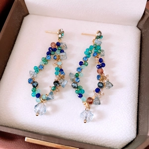 Macro shot of colorful beaded tassel earrings with crystal clusters and gold-toned needles