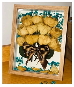 Detail of wooden shadow box frame featuring yellow dried roses and blue baby's breath