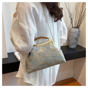 Detail view of floral embroidery on light blue satin handbag with resin handle