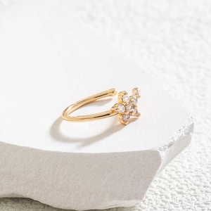 Close-up of golden star-shaped ear cuff with clear crystals on a white stone base