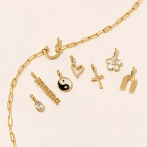 Gold paperclip chain necklace with diverse charms including Mama word and enamel heart