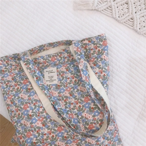 Detailed top view of a large capacity floral canvas tote bag on soft white bedding