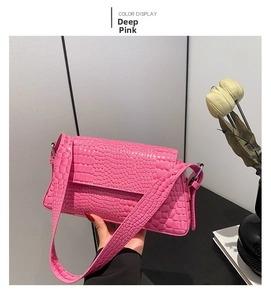 Detail view of dark pink crocodile-embossed leather handbag with metallic hardware