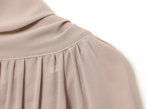 Detalle macro de la costura plisada del hombro en un vestido de gasa rosa empolvado