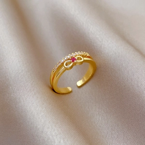Detail of gold bow ring featuring a red gemstone and white zircon pavé setting