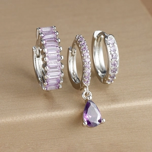 Macro detail of silver geometric earrings set featuring purple zircons and teardrop pendant
