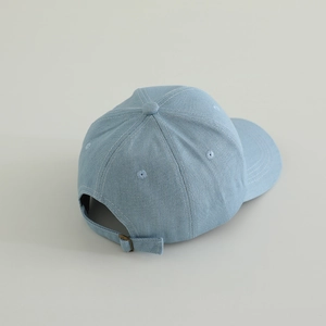 Close-up of the light blue denim baseball cap's adjustable metal buckle and stitching