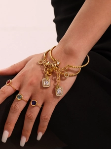 Close-up of gold stainless steel twisted bracelets with zircon and colorful gem rings