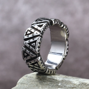 Macro shot of vintage titanium steel ring with triangle patterns on grey stone surface