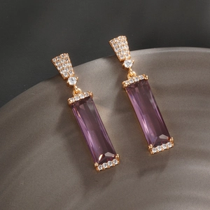 Gros plan de boucles d'oreilles pendantes en zircon violet avec monture dorée pavée