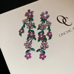 Macro view of crystal flower tassel earrings with pink gems and green marquise stones