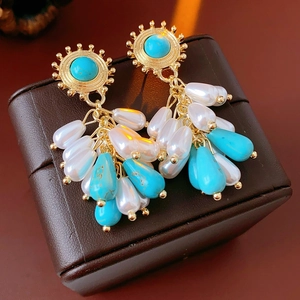 Detail of vintage bohemian tassel earrings with pearls and turquoise on leather background