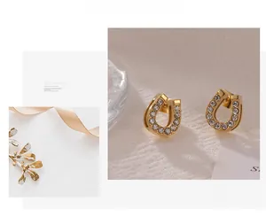 Detailed close-up of golden U-shaped horseshoe earrings with sparkling inlaid rhinestones
