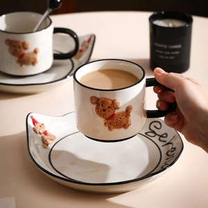 Detail of hand-painted ceramic dog mug with 3D teddy puppy and red bow on white cup