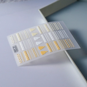 Detailed close-up of 5D embossed knitting pattern nail art stickers in white and gold colors
