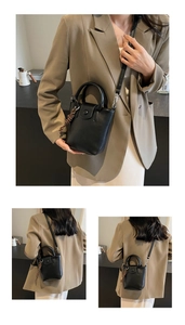 Detail view of stylish black leather bucket bag with top handle and woven ornament
