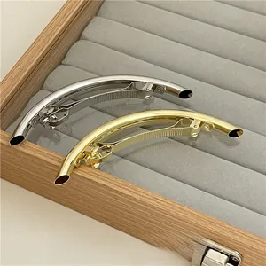 Detailed view of curved metallic gold and silver hair clips in a jewelry display box