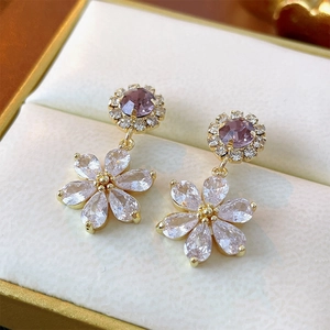 Sparkling floral drop earrings with purple zircon center and gold plating on jewelry box
